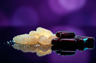 Cápsulas escuras de extrato de tart cherry e cristais de glicina emitindo um brilho calmante em ciano sobre uma superfície elegante de vidro negro, imersas num ambiente luxuoso roxo e violeta.